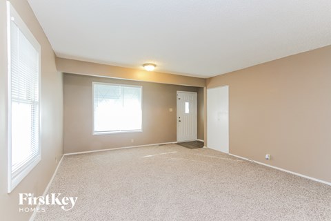A spacious room with a carpeted floor and a window letting in natural light.