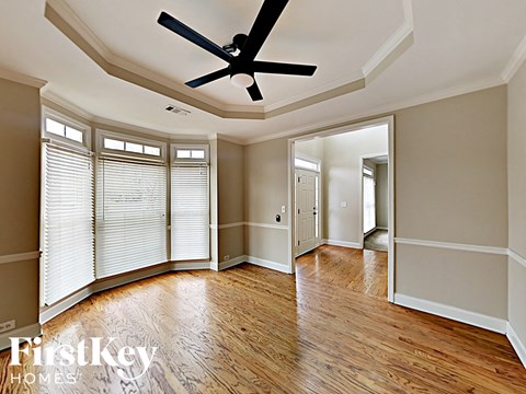 an empty living room with wood floors and a ceiling fan