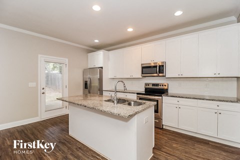 A kitchen with white cabinets and a granite countertop.