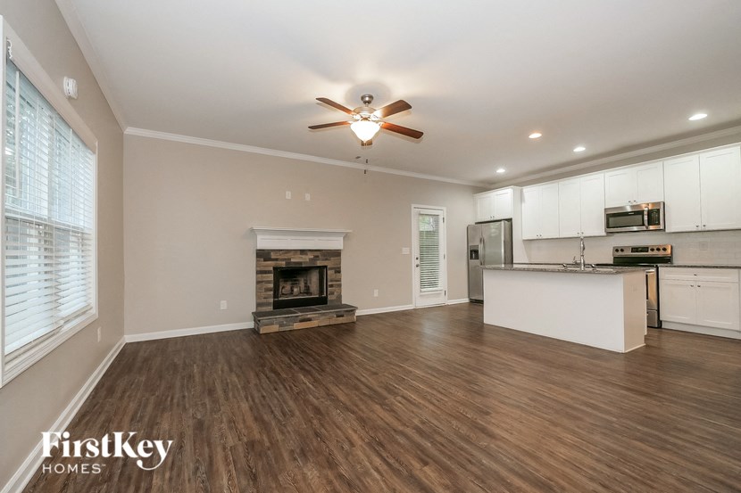 an empty living room with a fireplace and a kitchen