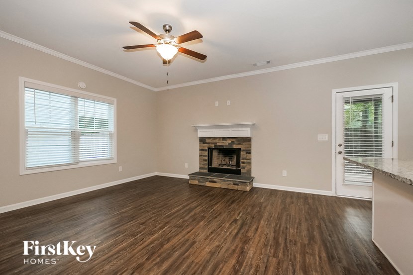 an empty living room with a fireplace and a ceiling fan