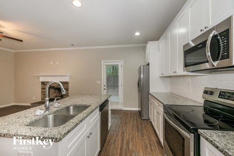a kitchen with granite counter tops and white cabinets and stainless steel appliances
