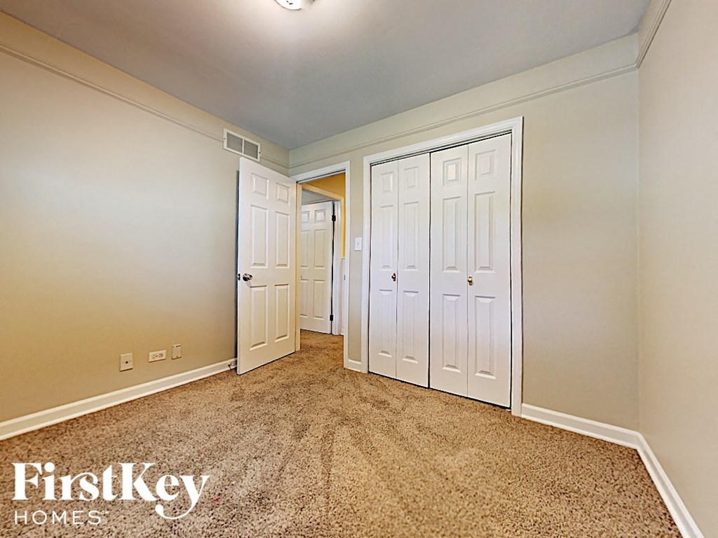 a bedroom with two closets and a carpeted floor and a door to a