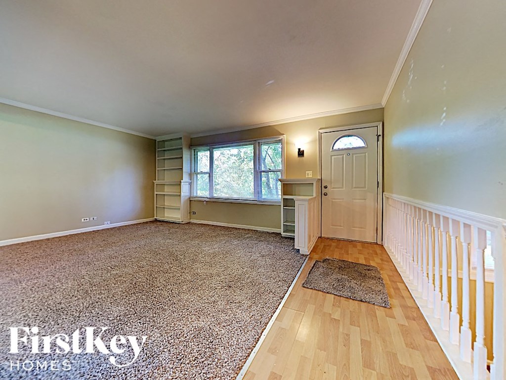 an empty living room with a staircase and a white door