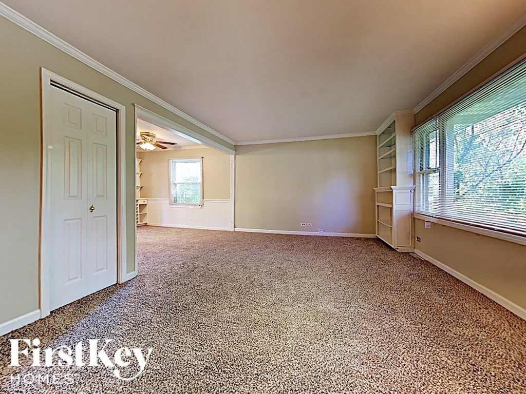 an empty living room with a large window and a white door