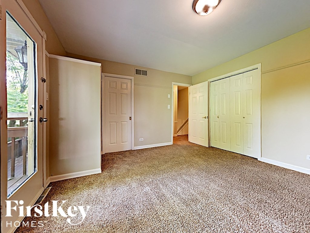 an empty living room with white doors and a carpeted floor