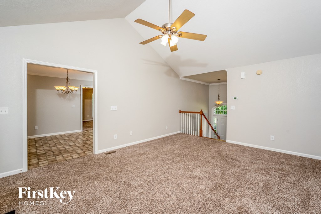 the spacious living room and dining room with carpeting and a ceiling fan
