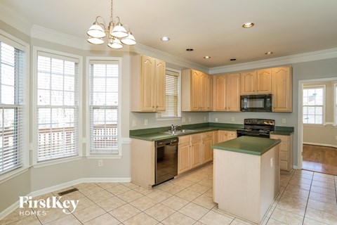 A kitchen with wooden cabinets and a green island.