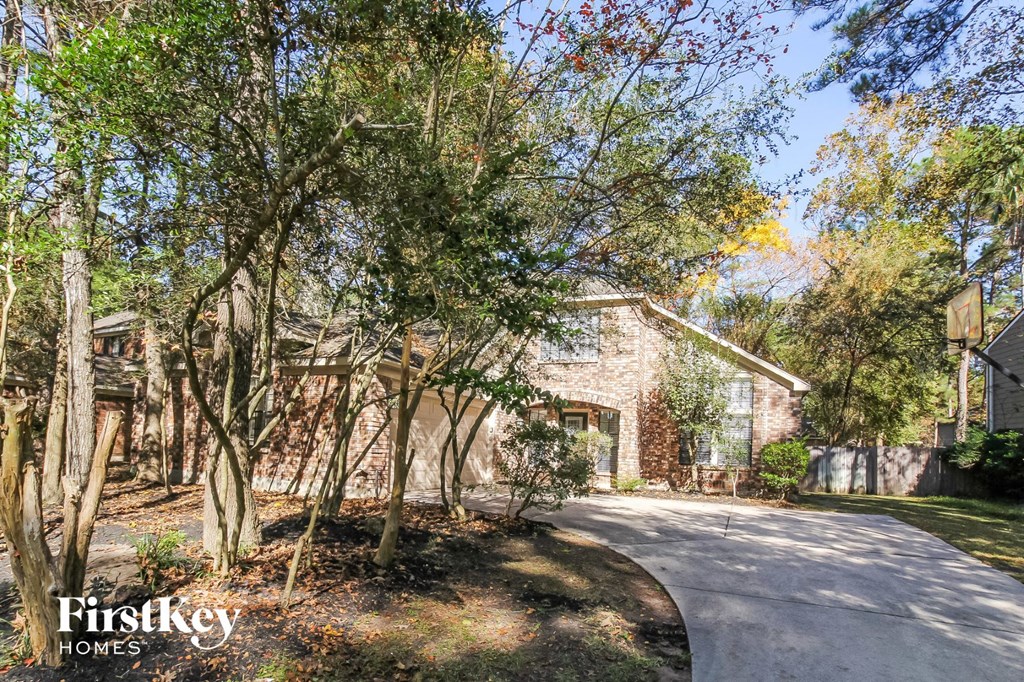 a driveway with trees in front of a brick house
