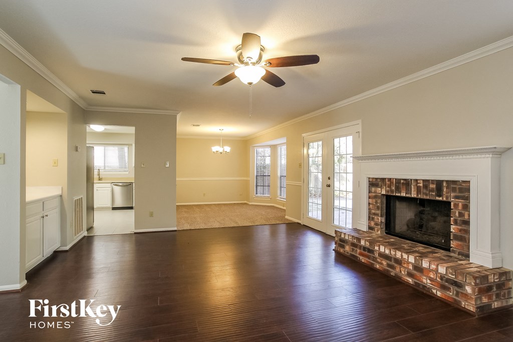 an empty living room with a fireplace and a ceiling fan