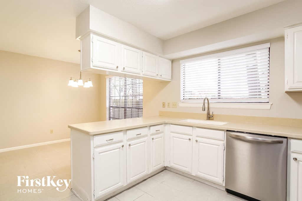 a kitchen with white cabinets and a stainless steel dishwasher