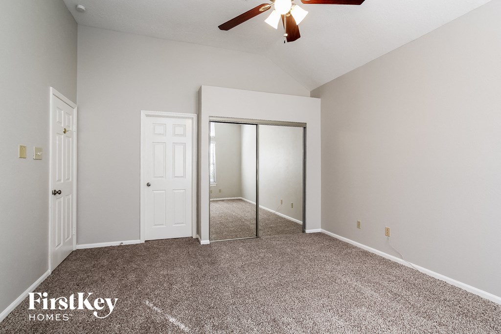 a master bedroom with carpeting and a ceiling fan