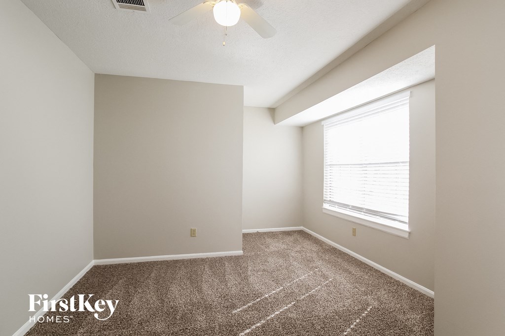 the spacious living room with carpeted flooring and a large window