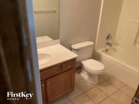 A white toilet sits in a bathroom next to a sink.