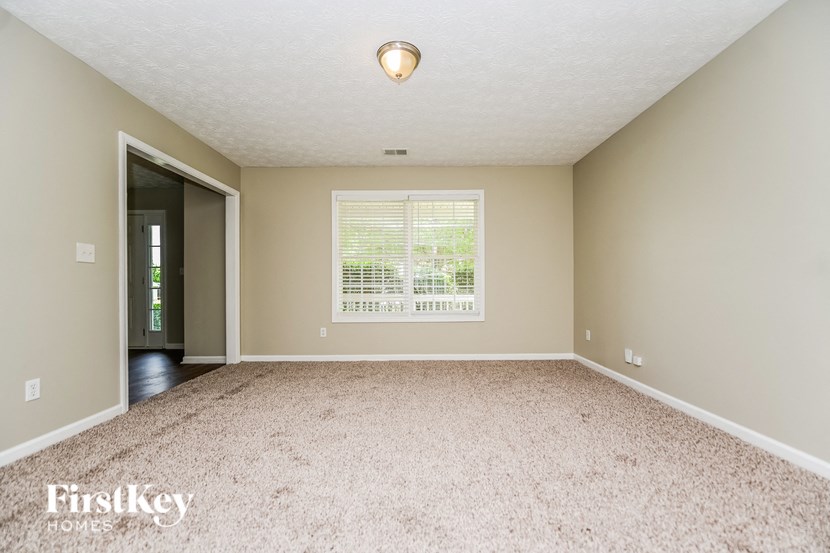 an empty living room with a large window and carpeting
