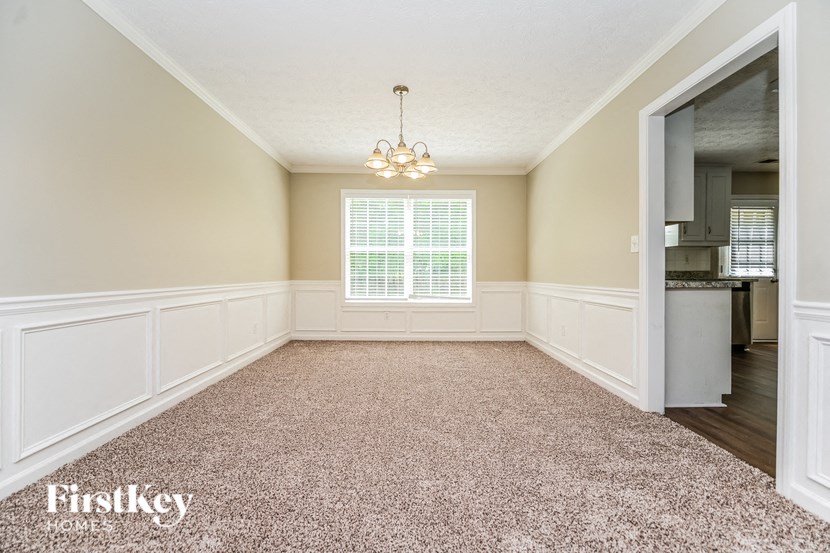 an empty dining room with a chandelier and a window