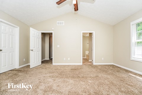 a spacious living room with carpet and a ceiling fan