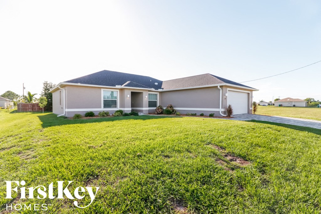 A house with a blue roof and a sign that says "FirstKey Homes" in front of it.