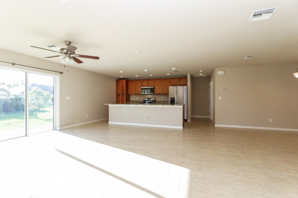 A spacious living room with a ceiling fan and sliding glass doors.