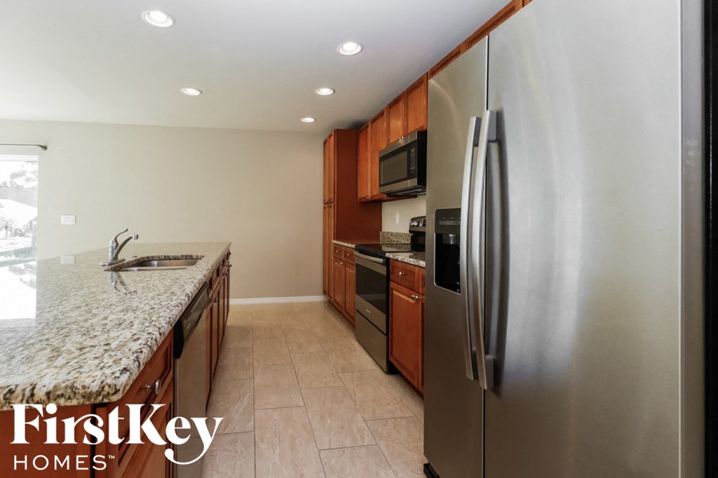 A kitchen with a refrigerator, sink, and cabinets.