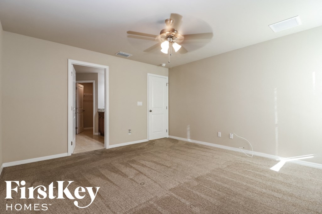 A spacious room with a ceiling fan and a carpeted floor.