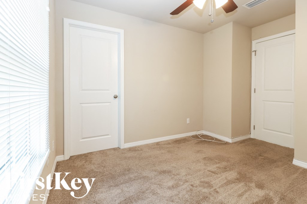 A room with a carpeted floor and two doors.
