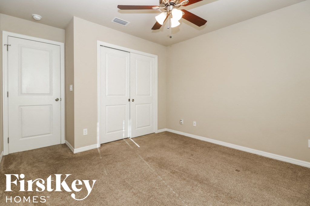 A room with a carpeted floor and a ceiling fan.