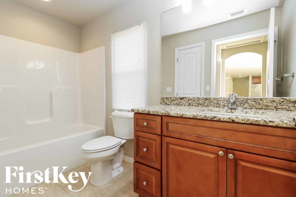 A bathroom with a granite countertop and a white toilet.