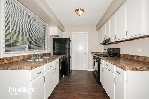 A kitchen with white cabinets and a granite countertop.