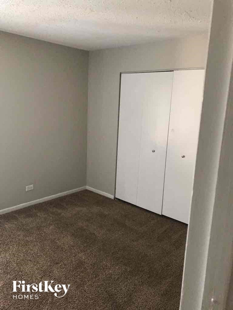 A carpeted room with a white closet door and a FirstKey Homes logo.