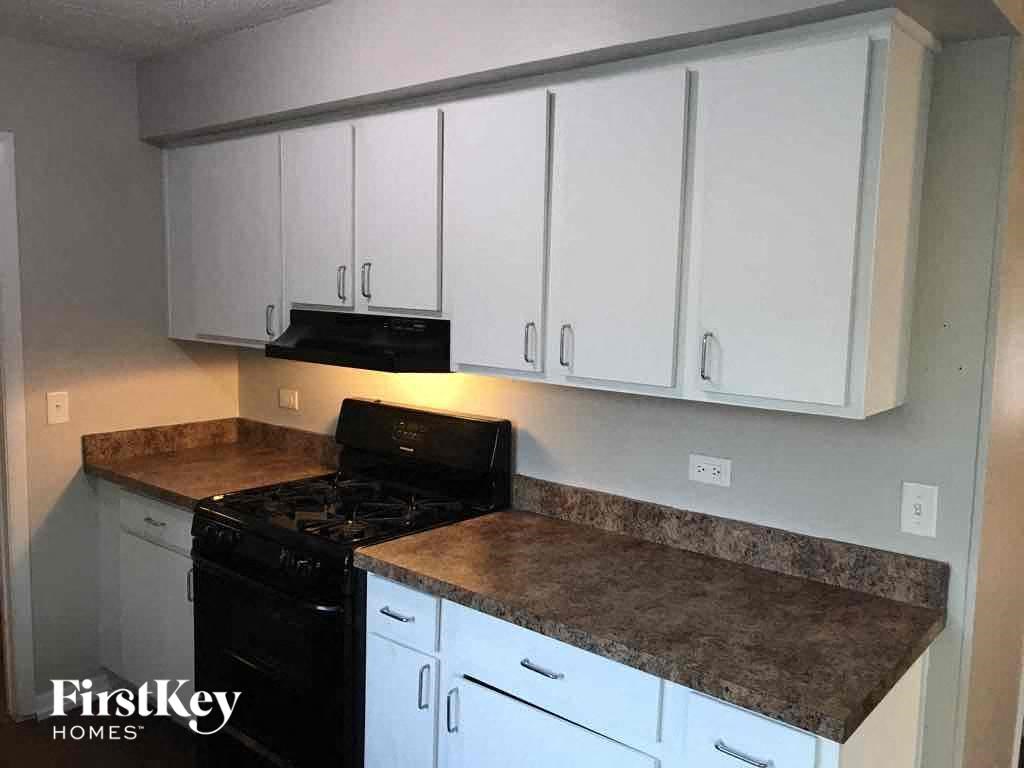 A kitchen with a black stove top oven and white cabinets.