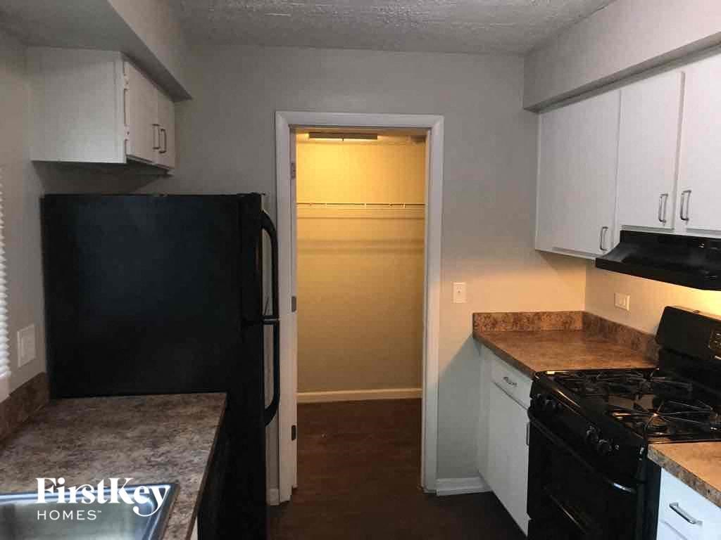 A kitchen with a black fridge and white cabinets.