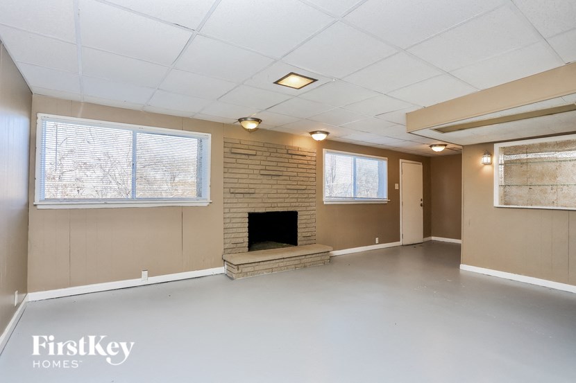 A spacious living room with a fireplace and a brick wall.
