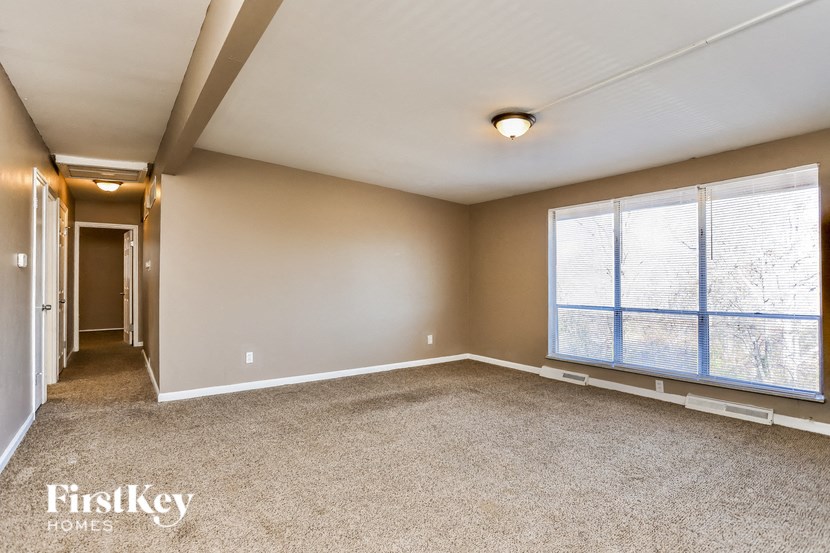 A spacious room with a carpeted floor and a large window.