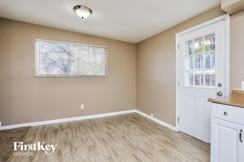 A room with a white door and a window with a view of trees.