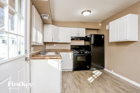 A kitchen with white cabinets and a black fridge.