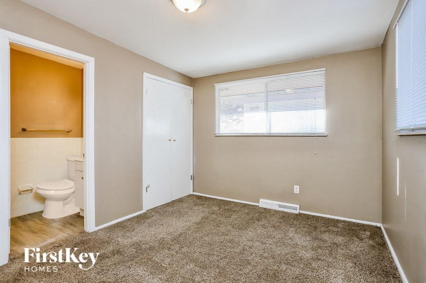 A bedroom with a toilet and a window.