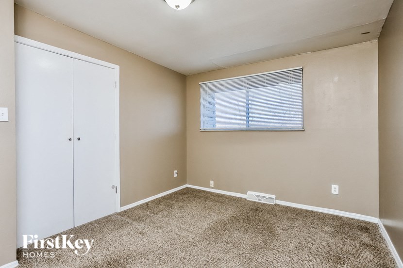 A room with a carpeted floor and a window with blinds.