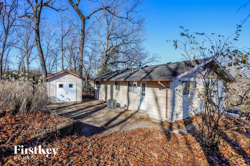 A house with a shed and a driveway in front of it.