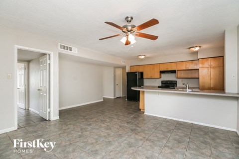 A kitchen area with a fan and a fridge.