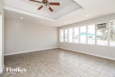 A spacious room with a ceiling fan and large windows.
