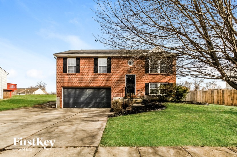 a brick house with a black garage door and a lawn