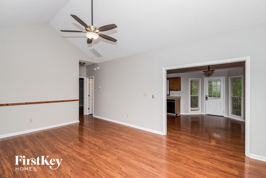the living room and dining room with hardwood floors and a ceiling fan