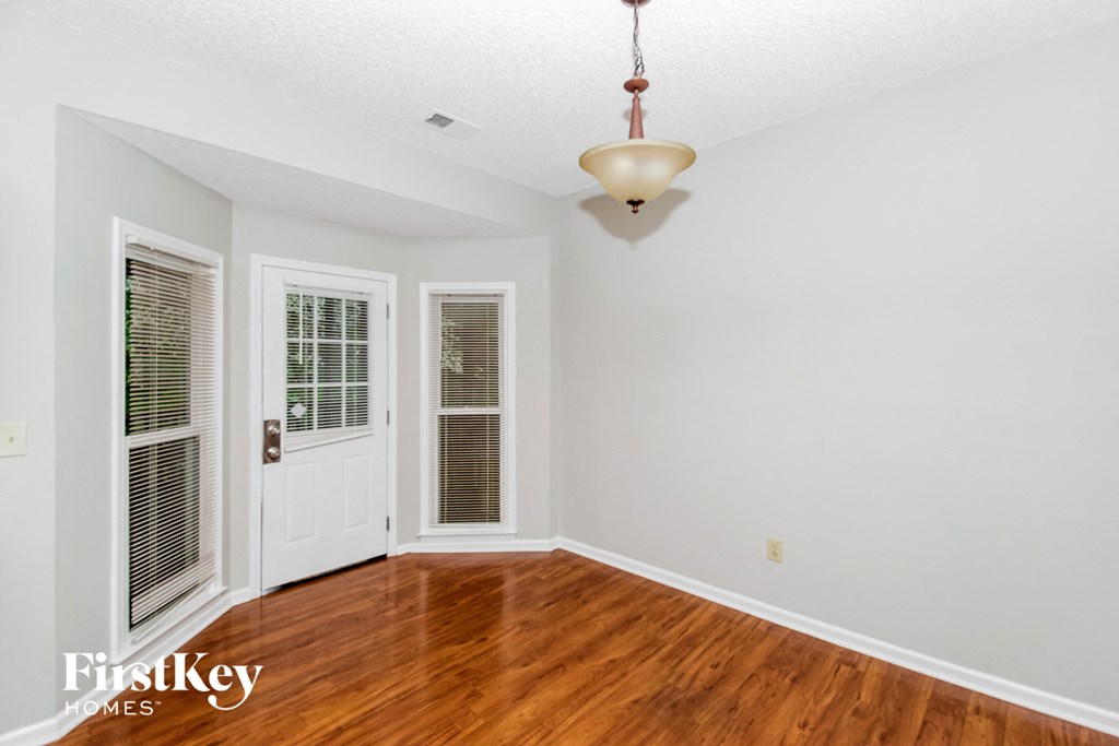 a living room with white walls and wood floors and a white door