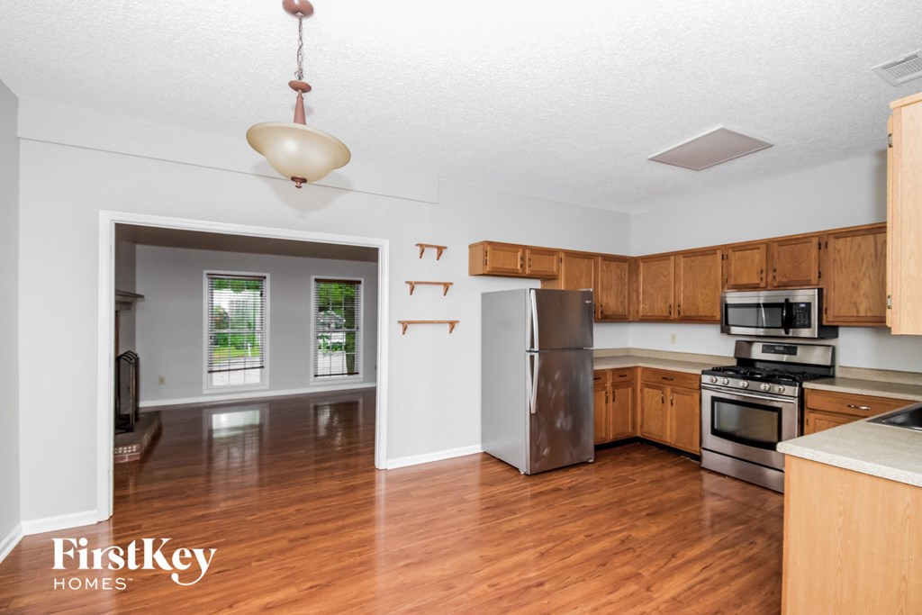 an empty kitchen with wooden cabinets and stainless steel appliances