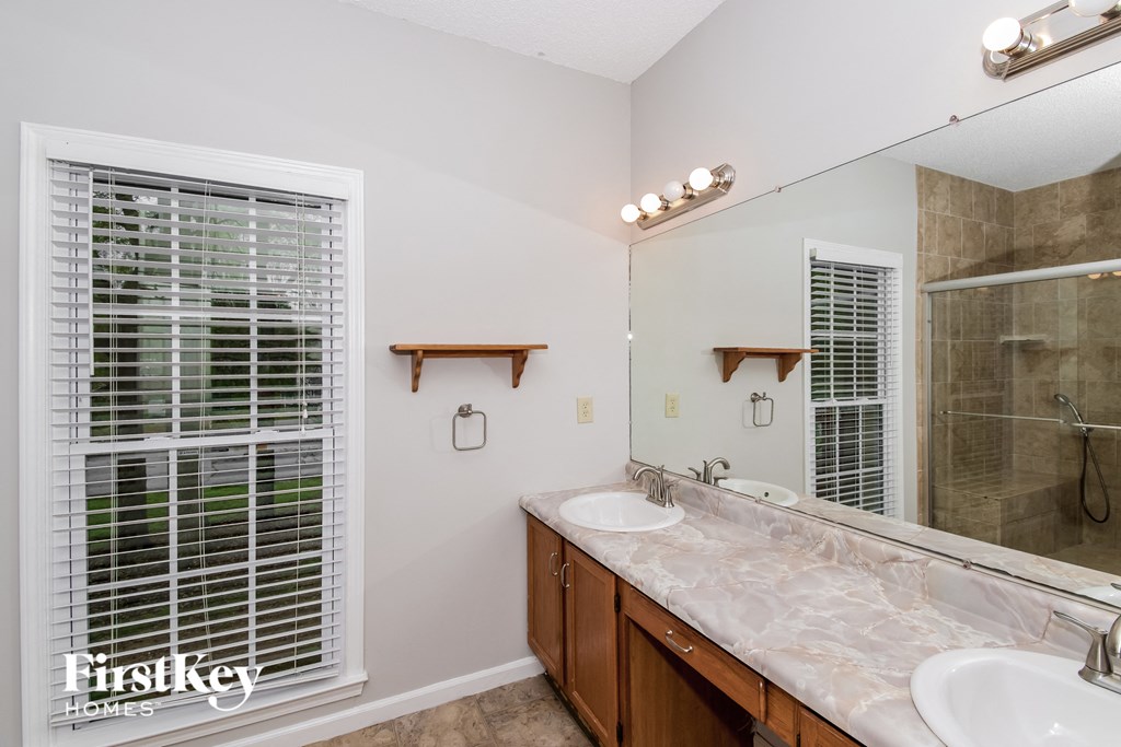 a bathroom with two sinks and a large mirror and a shower