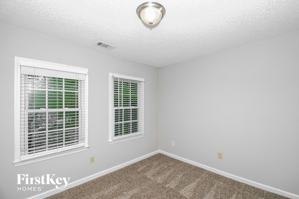 a bedroom with two windows and a carpeted floor