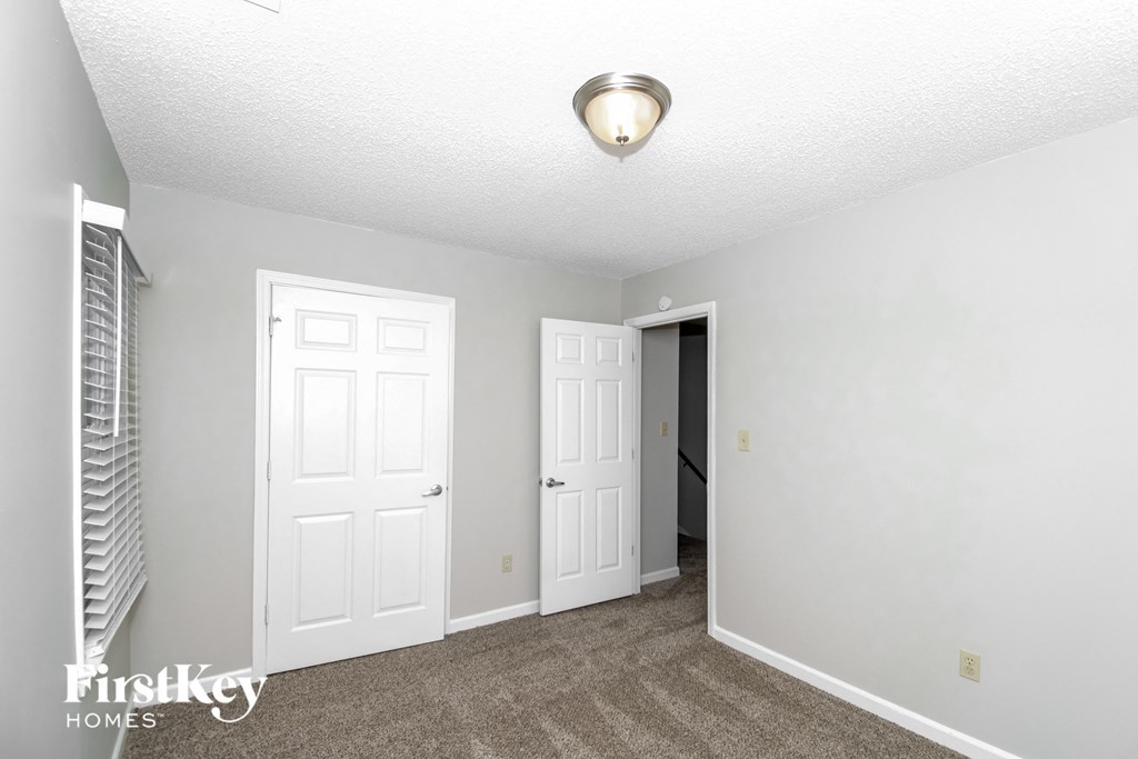 a living room with two white doors and a carpeted floor