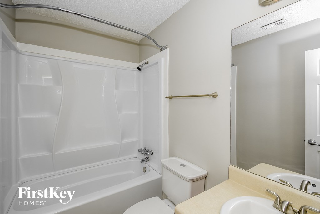 a white bathroom with a tub and a sink and a toilet