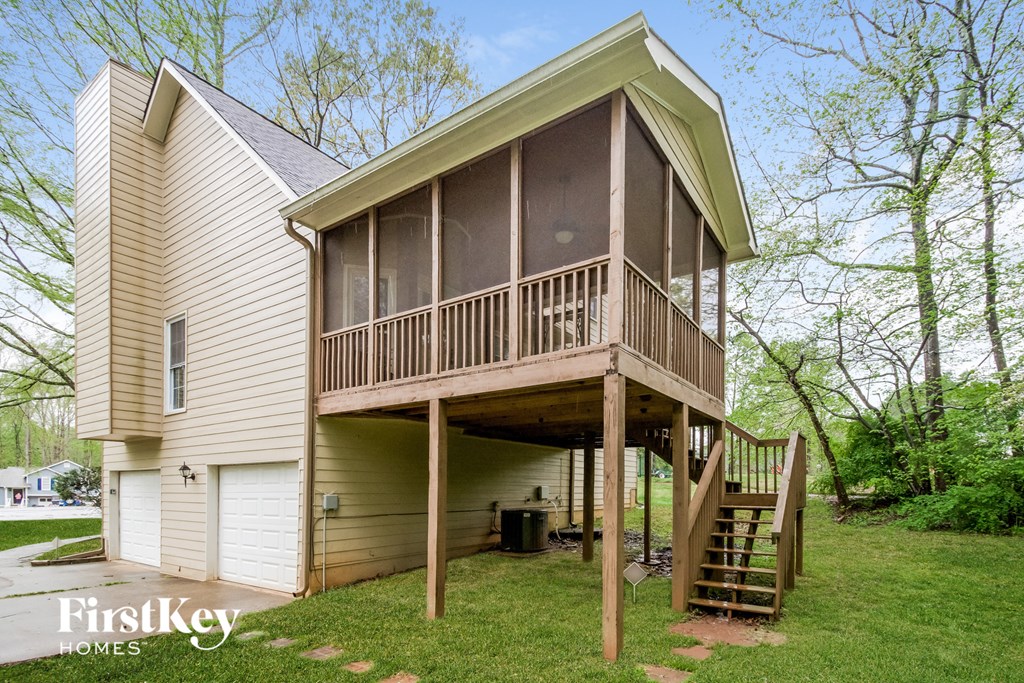 a house with a deck on top of a green lawn